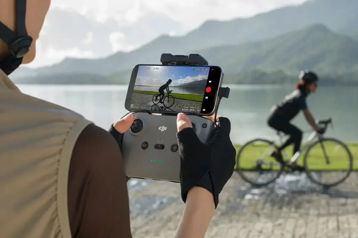 Mains tenant la télécommande DJI RC-N3, sticks et boutons de contrôle visibles