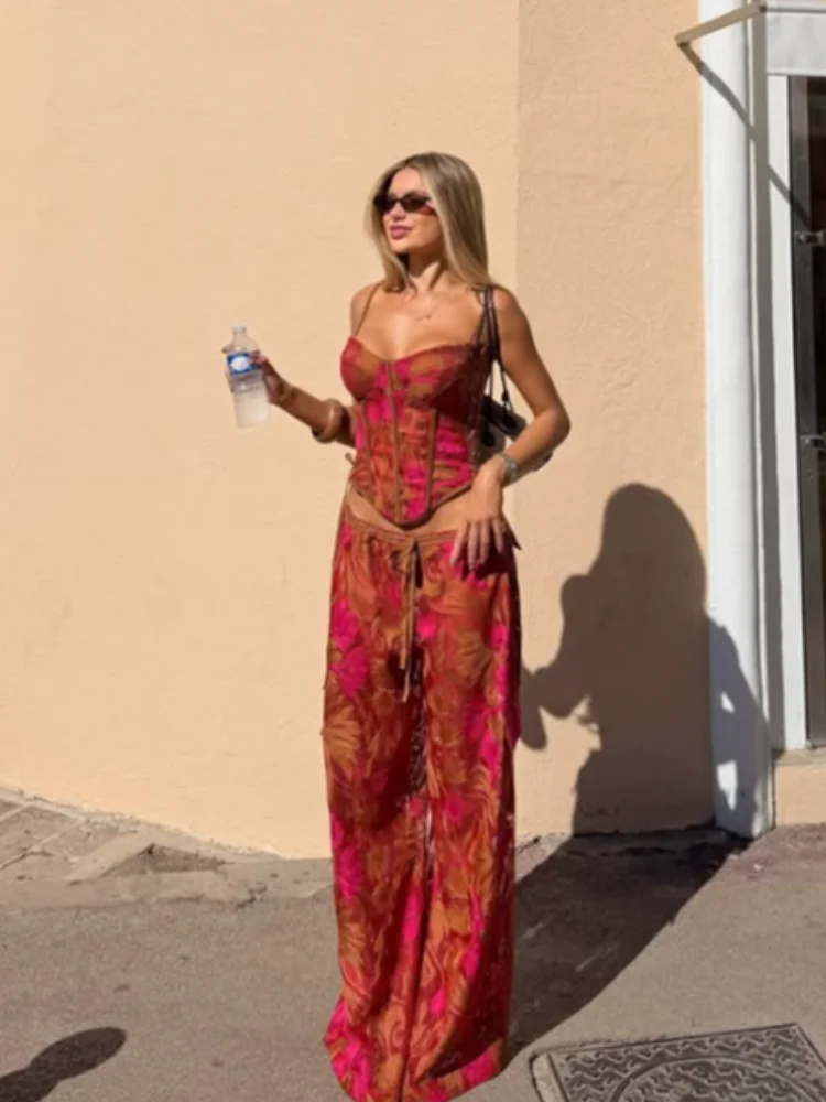 Ensemble floral en deux pièces, composé d’un corset à fines bretelles et de lacets, et d’un pantalon long à jambes larges avec cordon de serrage, idéal pour une tenue chic de vacances ou pour la plage. 1 Ensemble floral en deux pièces, composé d’un corset à fines bretelles et de lacets, et d’un pantalon long à jambes larges avec cordon de serrage, idéal pour une tenue chic de vacances ou pour la plage. 1