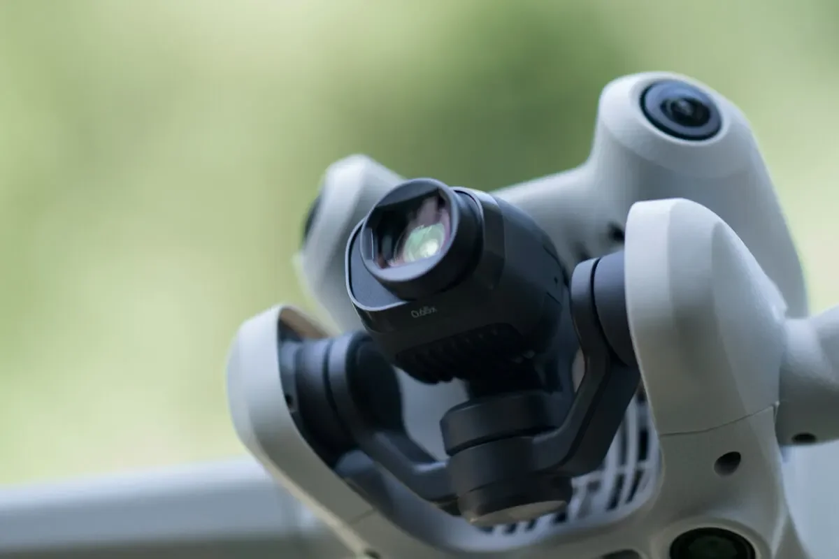 Drone DJI Mini 4 Pro équipé de l'objectif grand angle survolant une forêt dense
