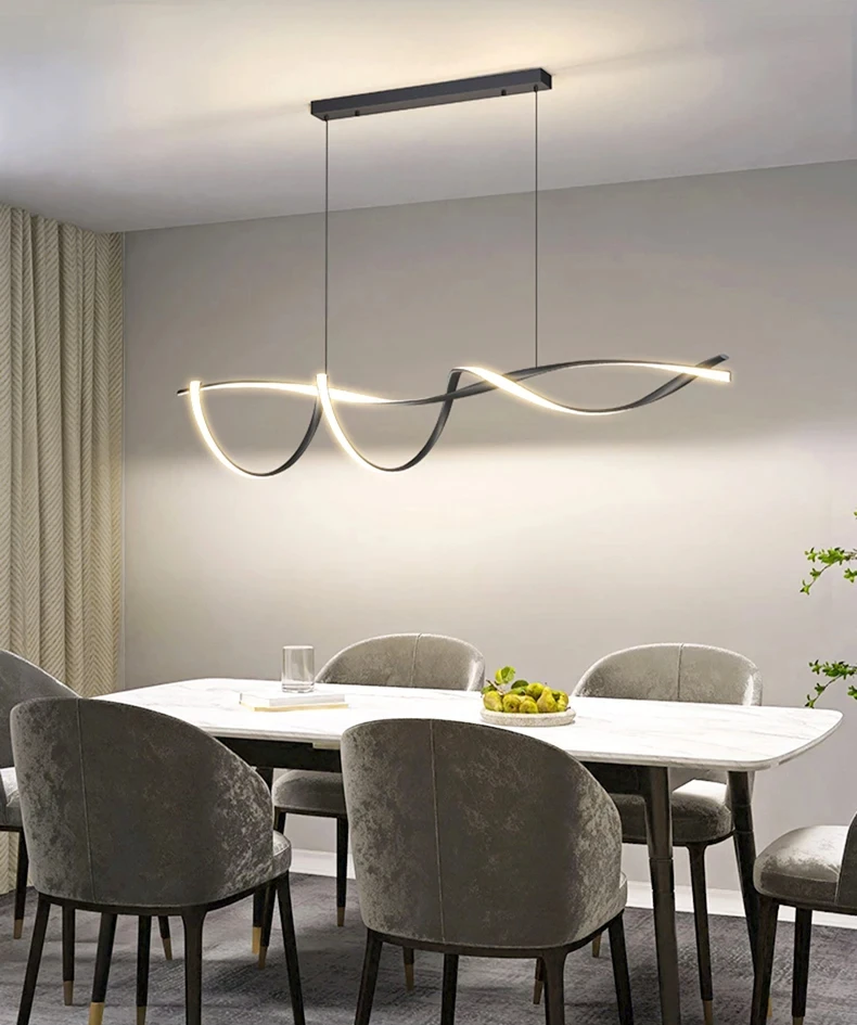 A modern dining room includes a white marble table with six gray velvet chairs under a Stylish Pendant Light. A bowl of green apples sits on the table, with light gray curtains framing the space to enhance its minimalist design.