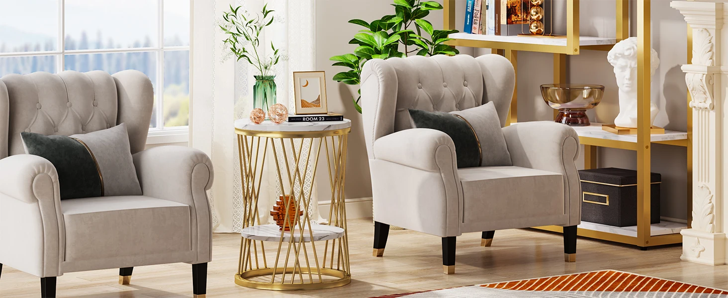 Zwei graue, getuftete Sessel in einem Wohnzimmer mit goldenem Beistelltisch, Pflanzen und Bücherregalen. Helles, modernes Innendesign