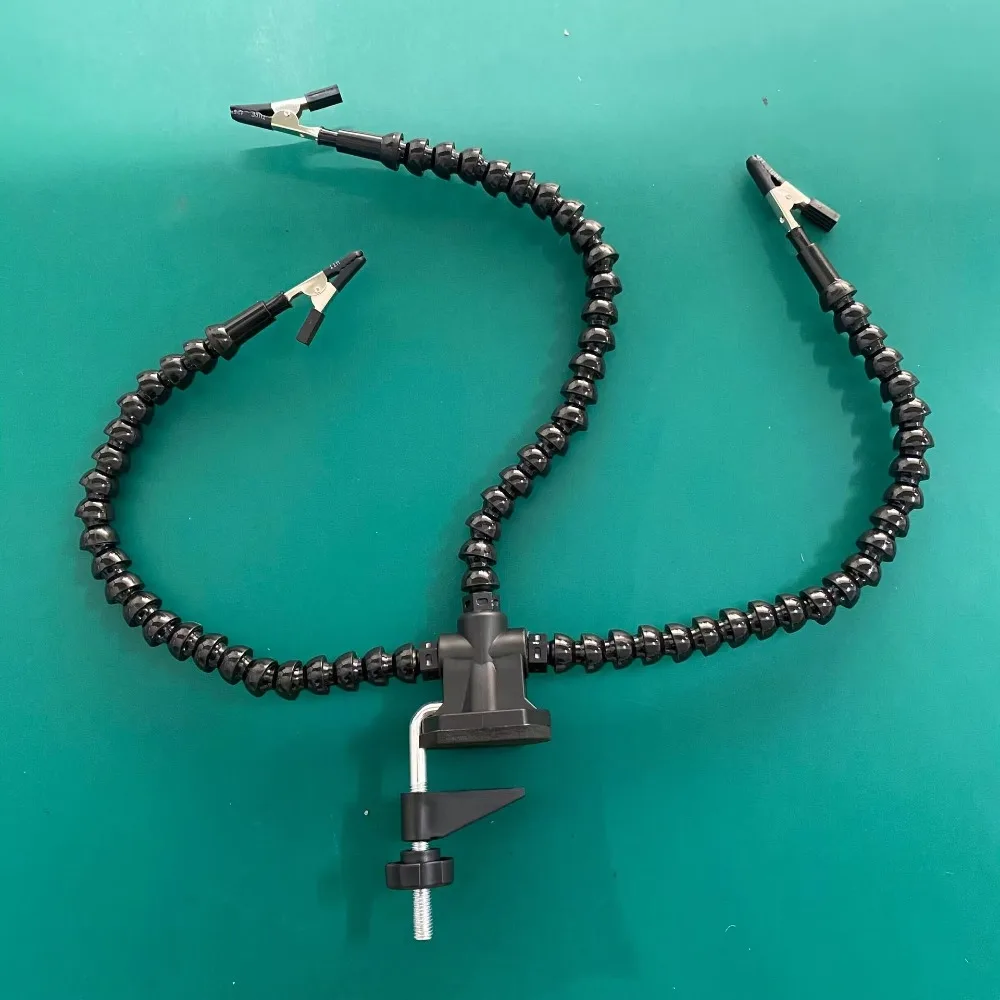 Bras flexible orientable de la table de soudage fixe pour modélisme, maintenant une pièce avec une pince crocodile.