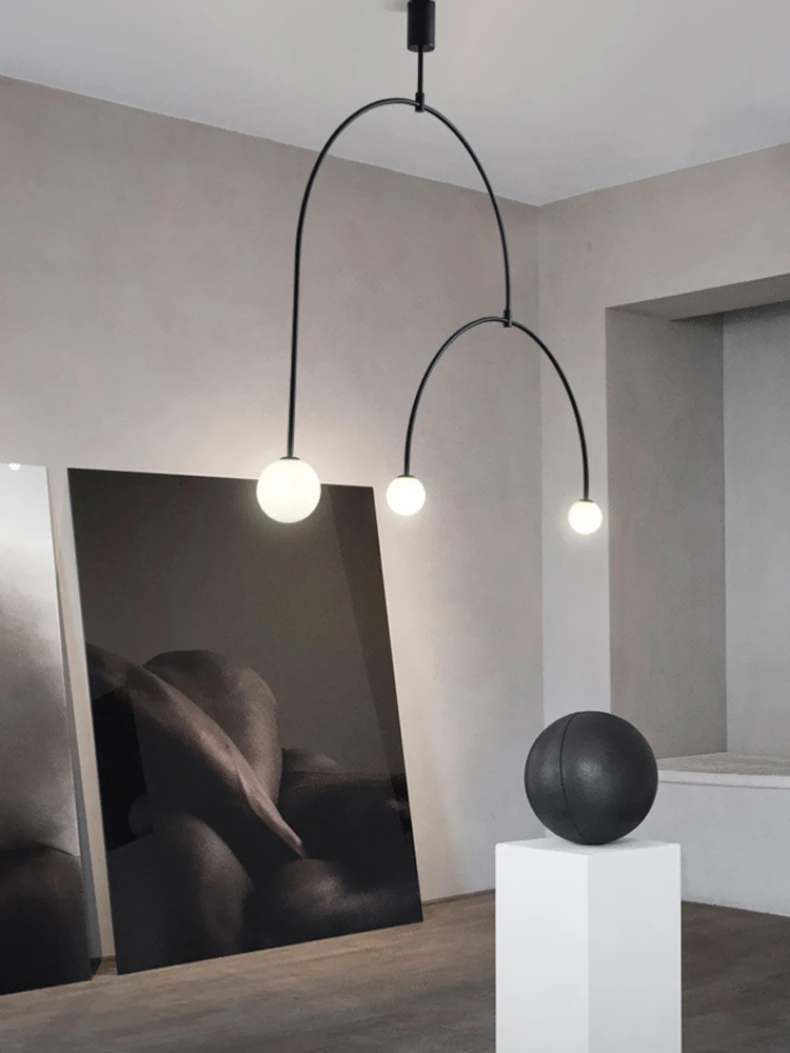 A minimalist room featuring the Minimalist Line Light, abstract paintings leaning against the wall, and a dark sphere on a white pedestal.