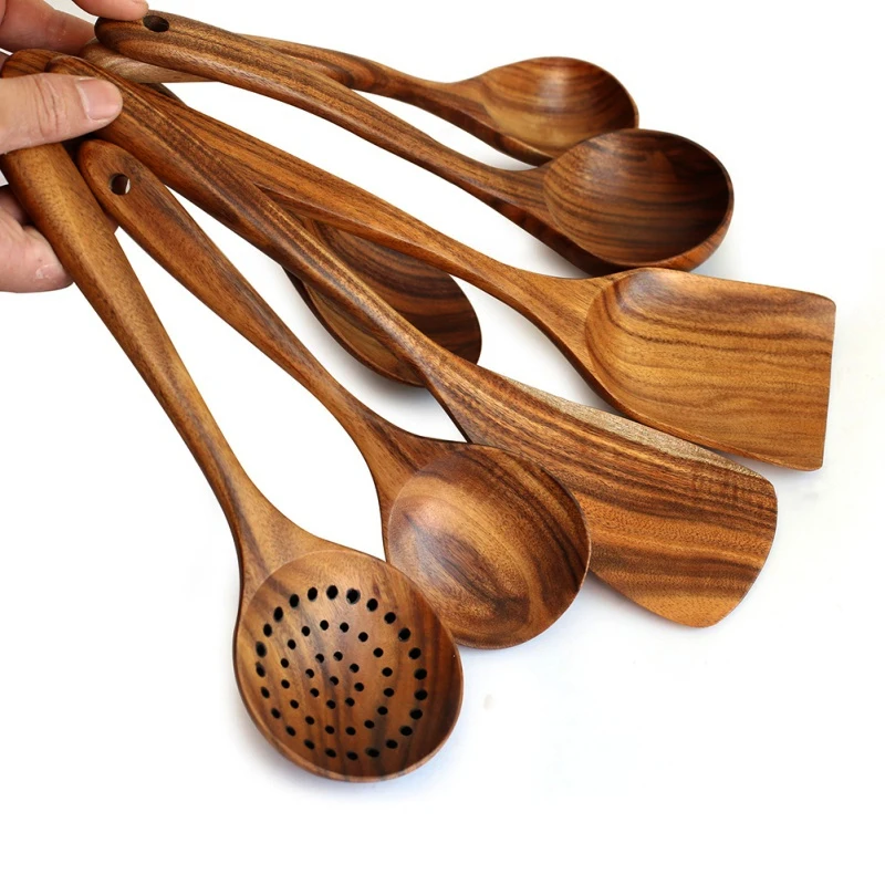Set of natural Thailand teak wood cooking utensils including ladles, skimmers, and spoons laid out on kitchen counter 02