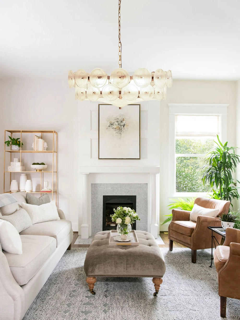 Bright living room with a white sofa, brown leather chairs, a plush ottoman, an Italian Retro Pendant Light, a fireplace, and large windows letting in natural light.