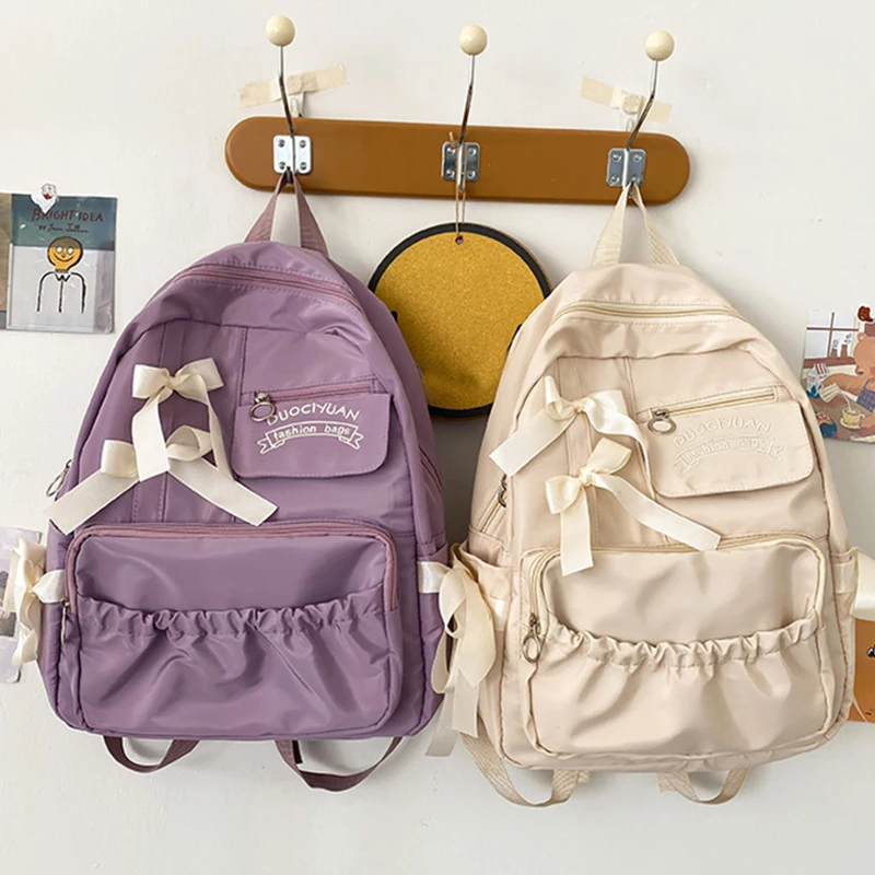 Stylish kawaii backpack with bowknot detail, designed for women and girls, featuring soft pastel tones and spacious compartments for school essentials. purple and beige