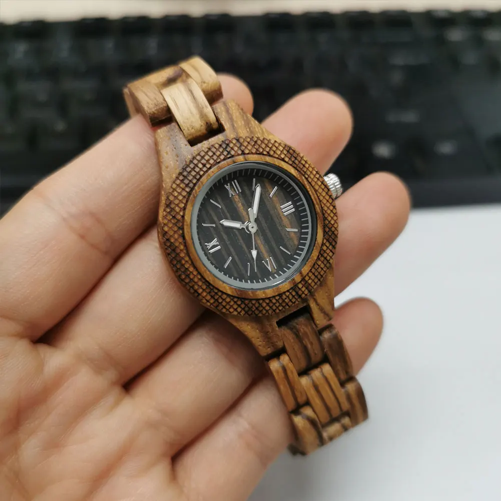 Puidust käekellade naistele lähivõte, mis näitab käekella tumedat sihverplaati ja puidu unikaalset tekstuuri, hoides seda kellegi käsi neutraalsel taustal.