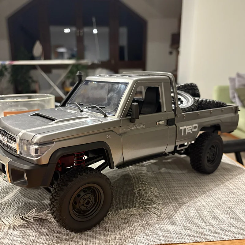 Vue latérale de la voiture télécommandée 1/12 4WD MN82, montrant ses pneus crantés et sa suspension.