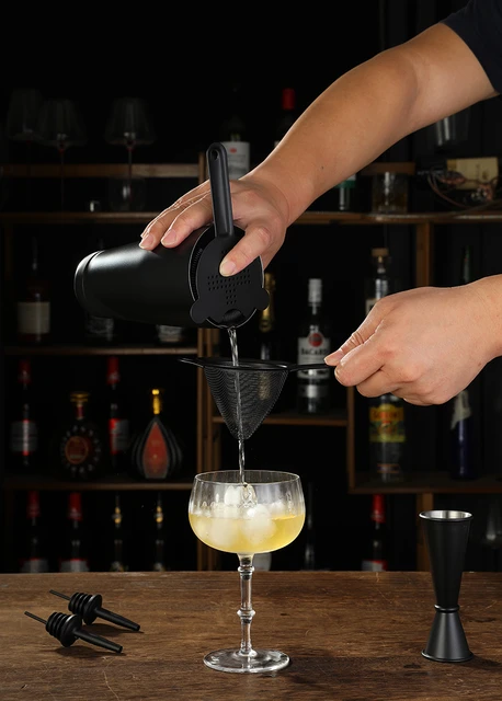 Bartender Holds In Hand Steel Jigger And Pours Drink From Bottle