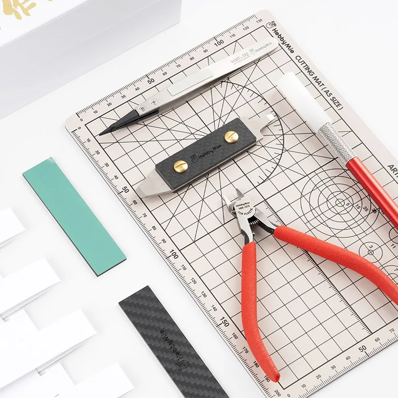 Planche de decoupe et tapis avec un kit de modelisme debutant, outils disposes.