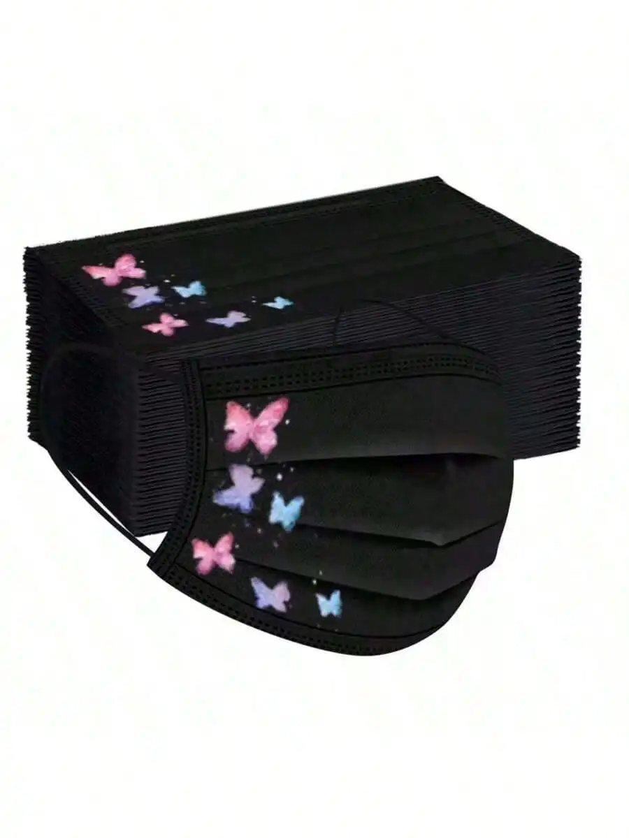 Masque réutilisable en tissu avec motif papillon rose et vert, plié sur une surface en bois, ambiance naturelle.