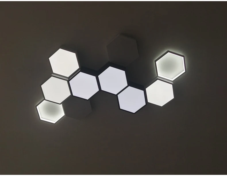 Hexagonal ceiling lights in a clustered arrangement on a dark background create adjustable lighting and visual interest.