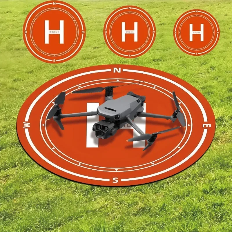 Tapis d'atterrissage pour drone rectangulaire noir déplié sur herbe, avec drone posé au centre, offrant protection et précision.