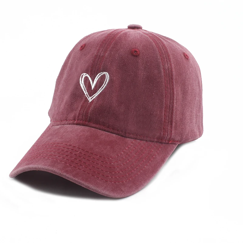 casquette en tissu délavé rouge avec une broderie en forme de coeur sur fond blanc