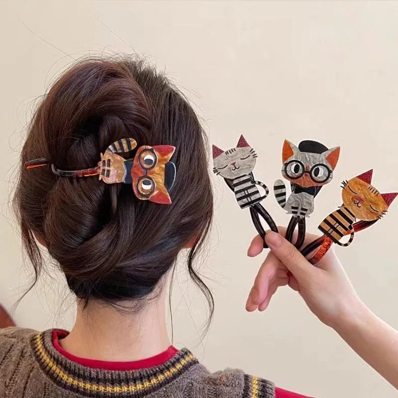A woman wears The Acrylic Cat Hairpin by KittyNook Cat Co. and holds three colorful, cat-themed hairbands.