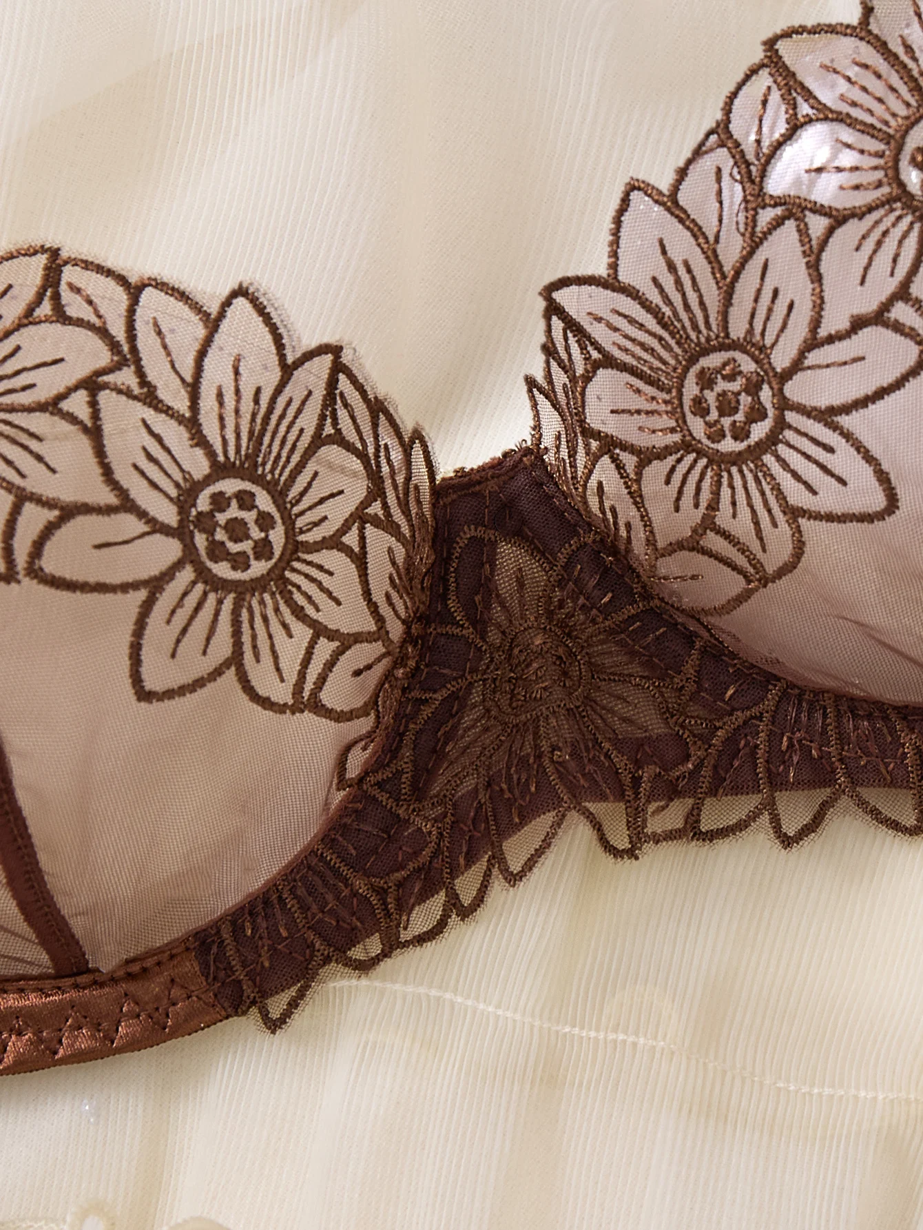 Close-up of embroidered flower detail with transparent mesh texture and delicate trim