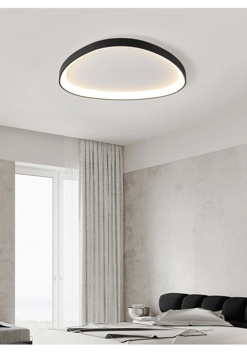 The Nordic Minimalist Ceiling Light, featuring a modern circular design with a black rim and dimmable brightness, illuminates a minimalist room adorned with gray curtains on a white rod, plain walls, and part of a dark headboard.