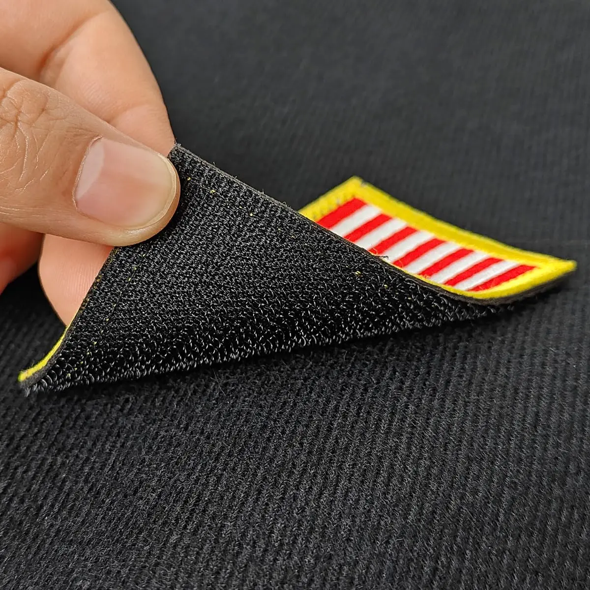 Hand holding a flag patch attaching it to a black patch display board