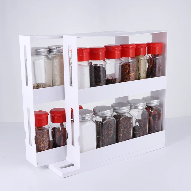 A white, 2-tier sliding cabinet organizer pulled out from a kitchen cabinet, showing neatly arranged spice bottles.