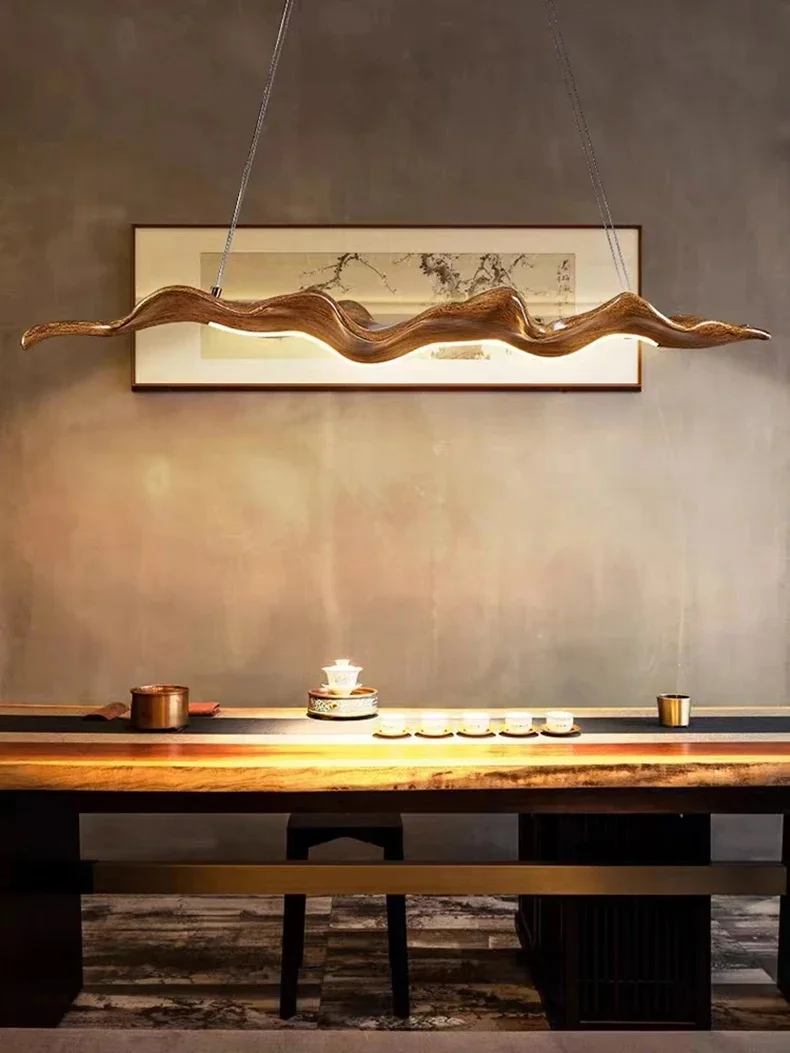 An elegant dining table set with teacups is illuminated by the Leaf Pendant Light, casting a warm glow, while a framed artwork adorns the wall above.