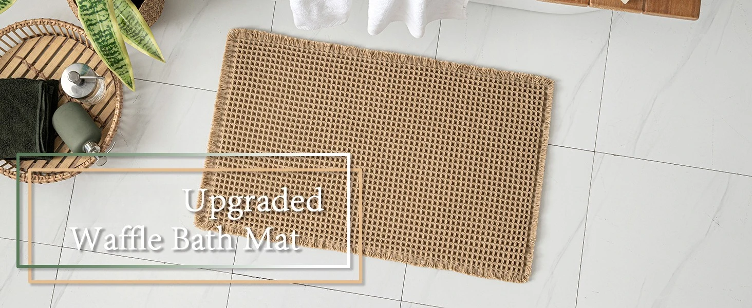 Soft beige boho waffle weave bath mat with fringe on a bathroom floor.