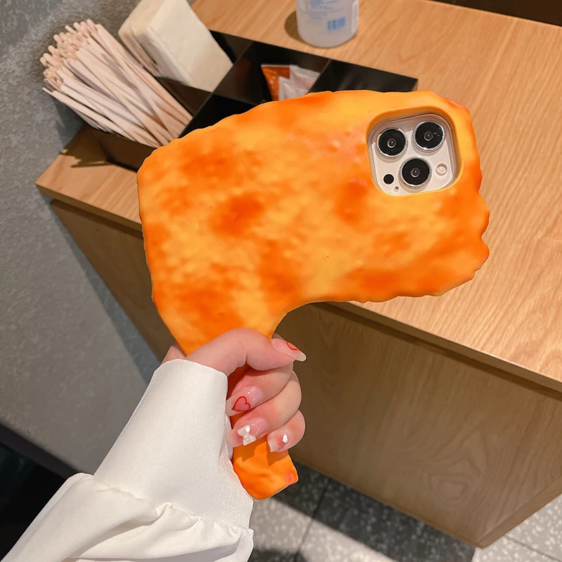 A hand holding a phone with a Chicken Drumstick iPhone Case in front of a wooden counter with stirring sticks and a white container.