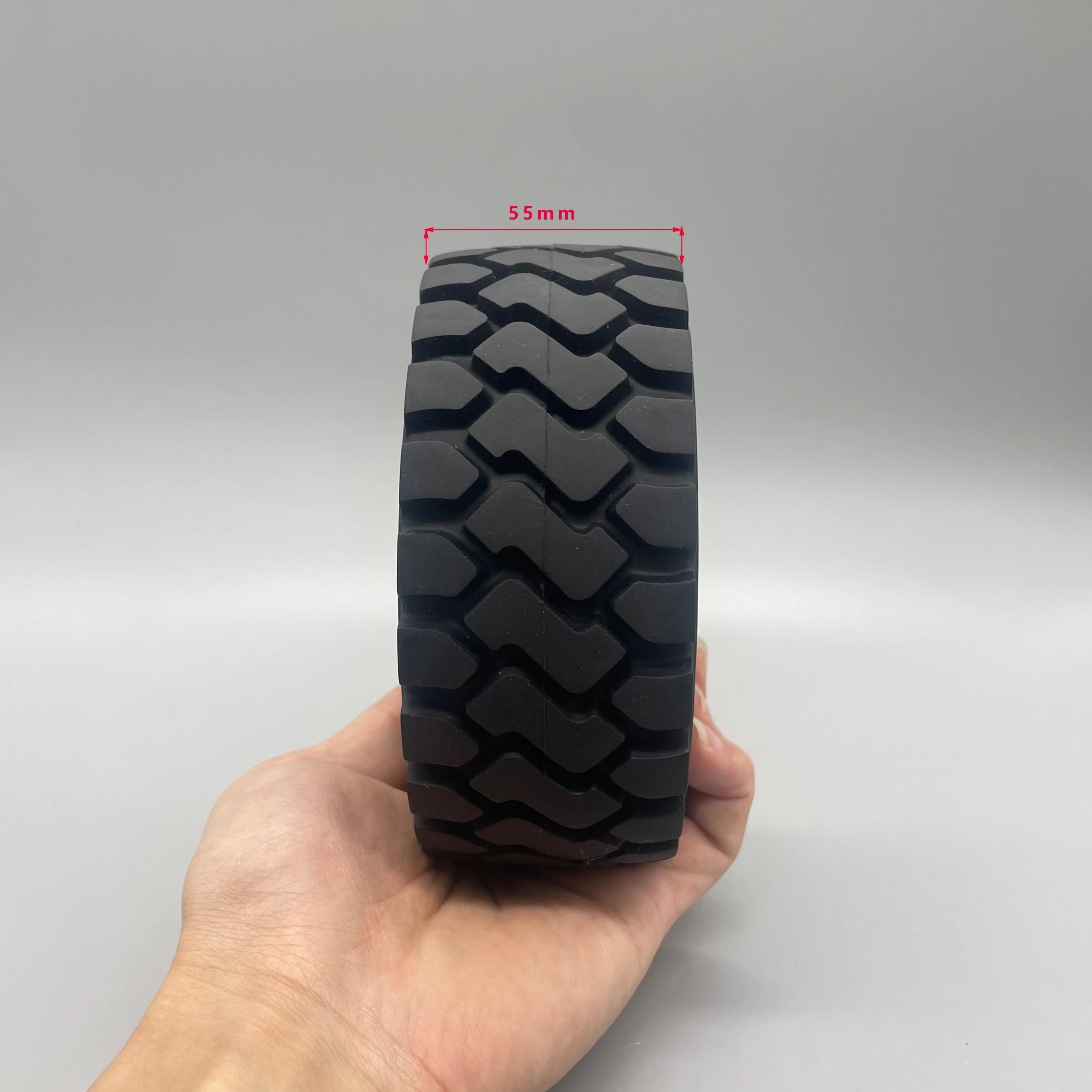 Pneus RC 137 mm pour bulldozer 1/14, empilés avec un ruban à mesurer pour indiquer l'échelle.