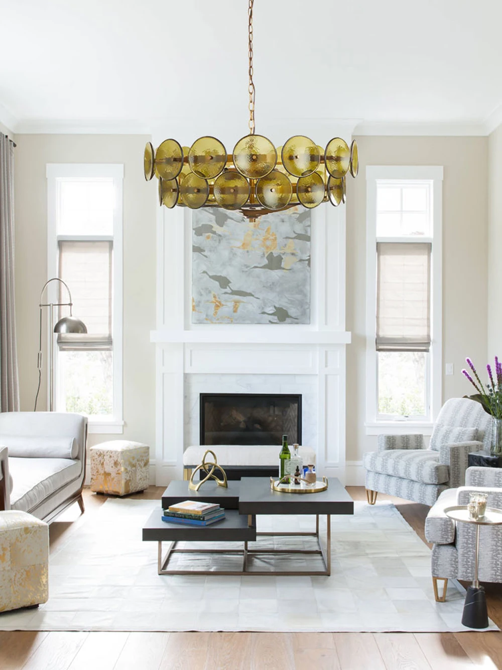 Modern living room featuring an Italian Retro Pendant Light, abstract art above a white fireplace, and neutral furniture arranged around a black coffee table on a light rug.