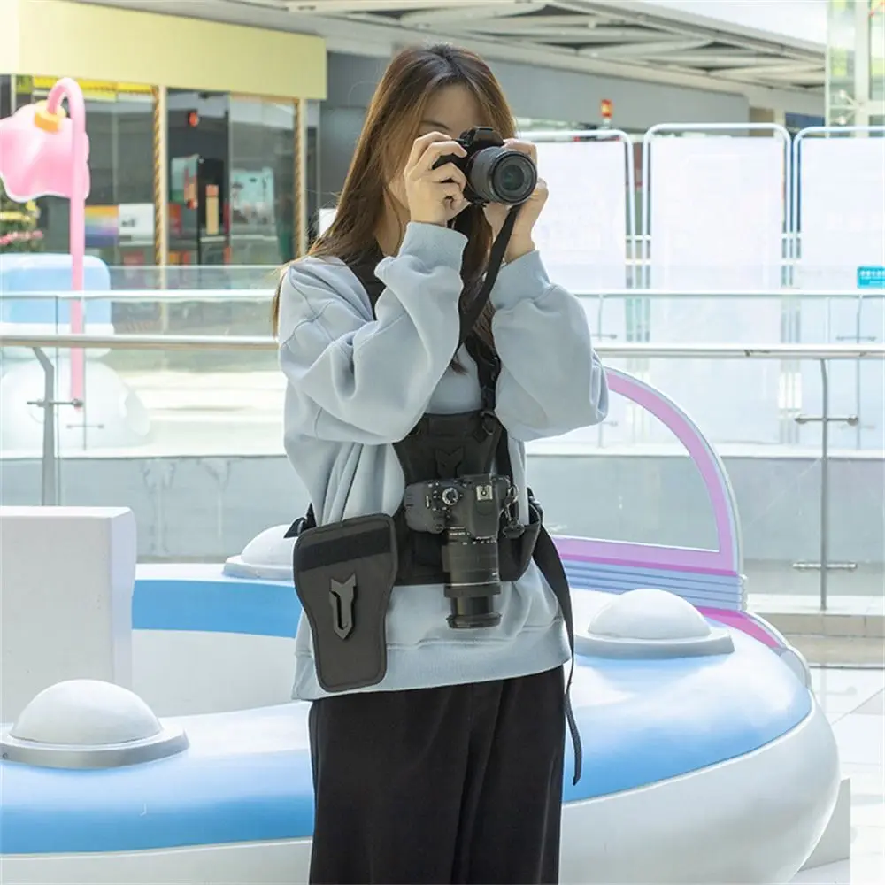 Harnais de poitrine pour appareil photo porté par un photographe, avec deux reflex accrochés, répartissant le poids sur les épaules.
