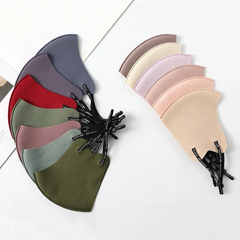 Deux masques réutilisables en tissu, protection lavable et confortable, pliés côte à côte sur une surface en bois.