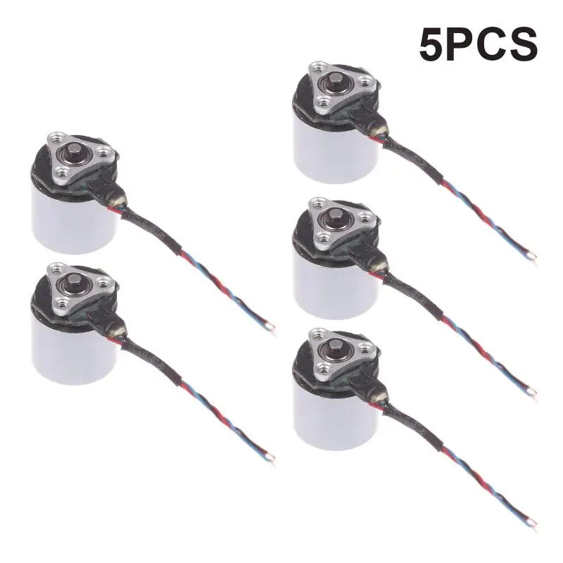 Micro moteur électrique métal argent 1.2x1cm tenu entre deux doigts pour échelle, arrière-plan flou.
