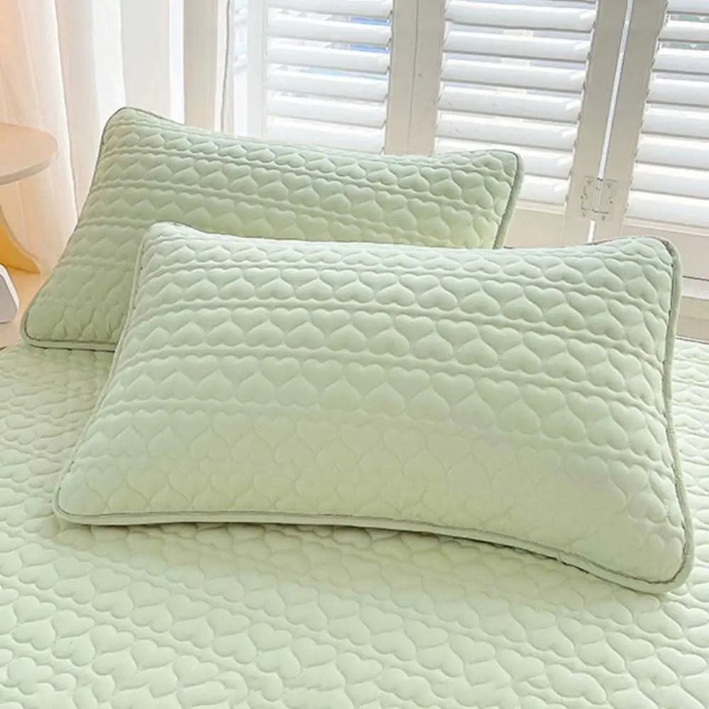 Green quilted pillow covers on a bed