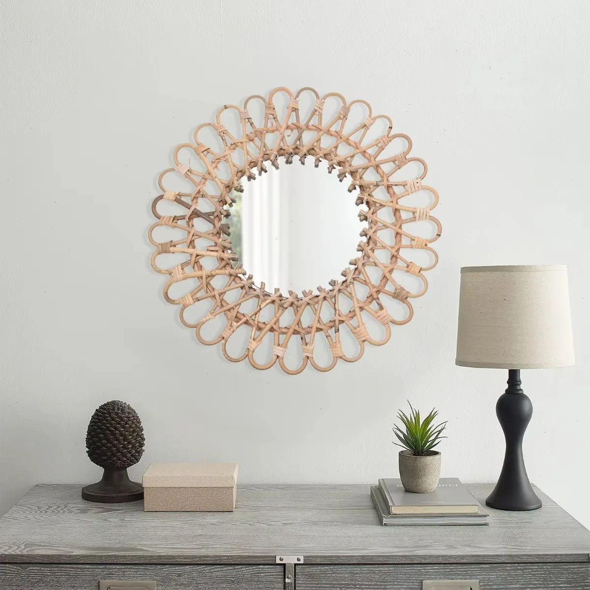 Rotan wandspiegel boven een grijze ladekast met lamp en kegel
