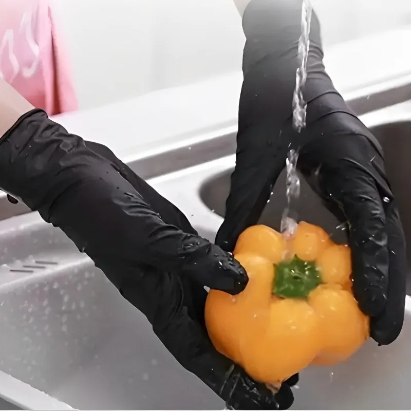 Gants nitrile jetables noirs et jaunes, empilés sur une surface blanche, vue de dessus.