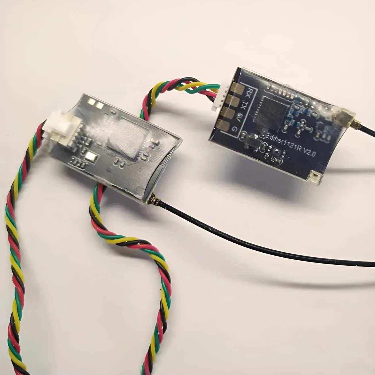 Vue rapprochée du module radio ELRS TX avec ses ports de connexion et dissipateur thermique.
