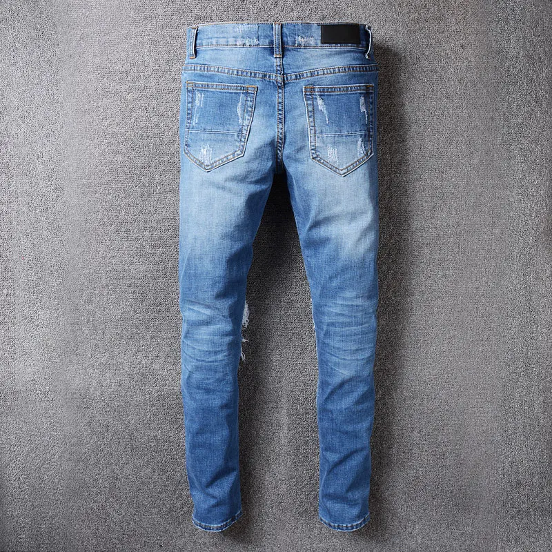 Fashionable street men's blue jeans. Elastic slim fit retro slit jeans with distressed patches. Designer hip-hop brand pants