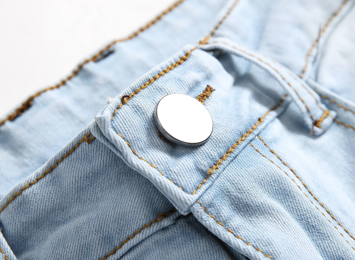 Close-up of button-zip fly on light blue Valroze™ Embroidered Denim Jeans