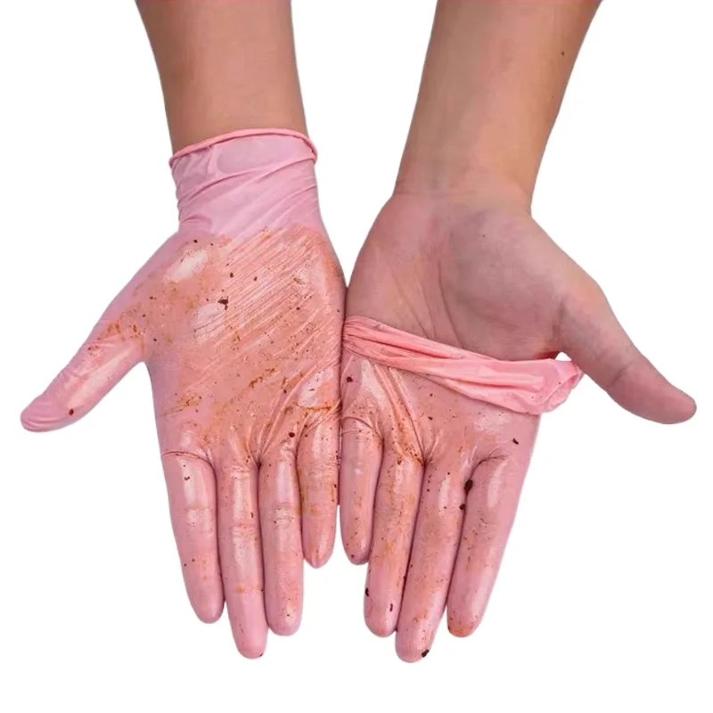 Stack of pink nitrile gloves fanned out beside cleaning tools and salon accessories on a white countertop