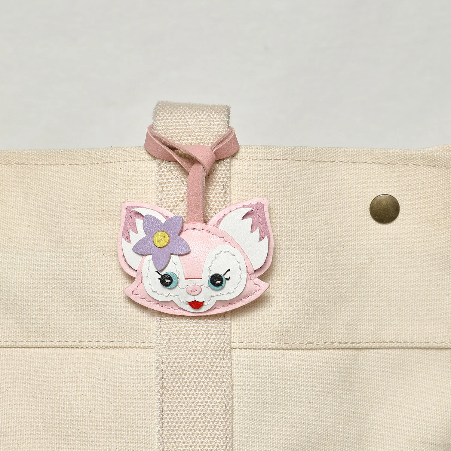 Pink fox leather bag charm attached to handbag