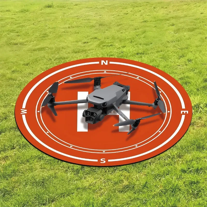 Pad d'atterrissage pour drone circulaire en tissu non tissé imperméable, posé sur herbe avec drone quadricoptère.
