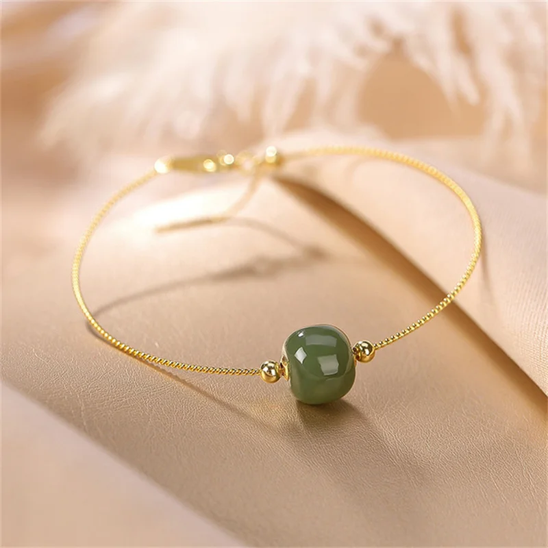 Lot - AN 18K YELLOW GOLD, JADE, AND DIAMOND HINGED LADY'S BANGLE BRACELET,  MODERN,