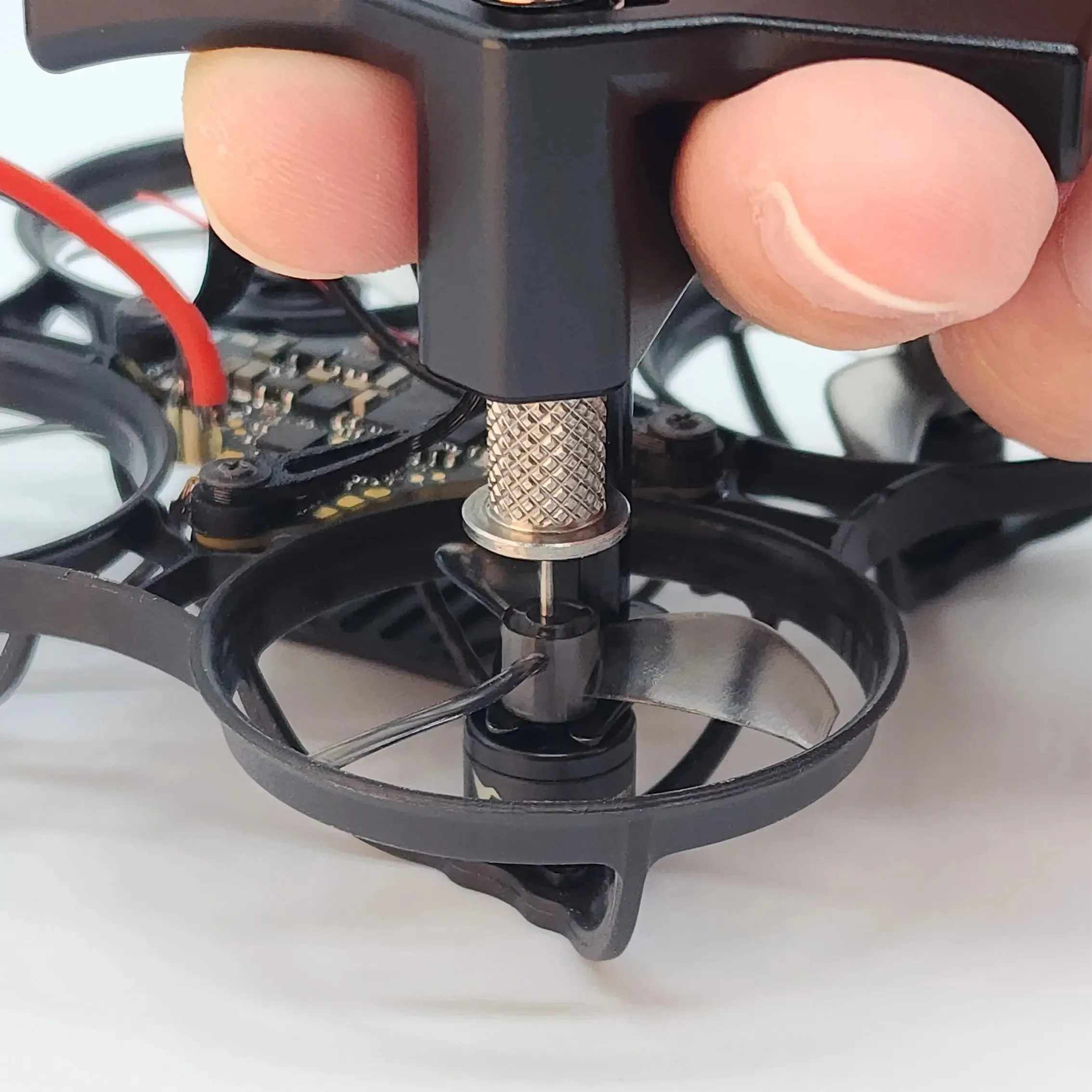 Gros plan sur l'outil NewBeeDrone Whoop PropyPop, montrant les embouts métalliques pour retirer les hélices Tiny Whoop sans effort.