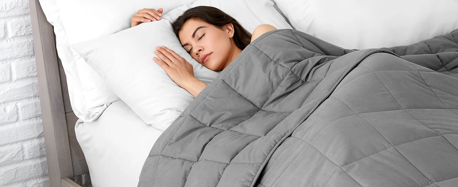 Women sleeping in bed with weighted blanket over her