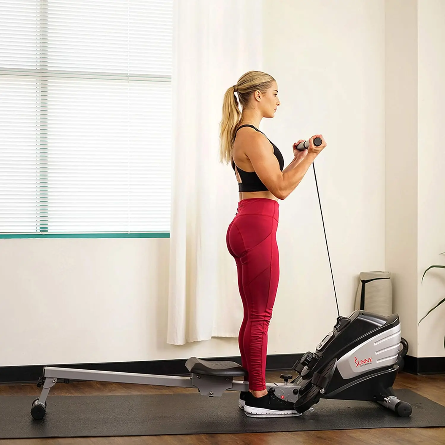 A woman working out with a sunny magnetic rowing machine sold by 100 Spartans
