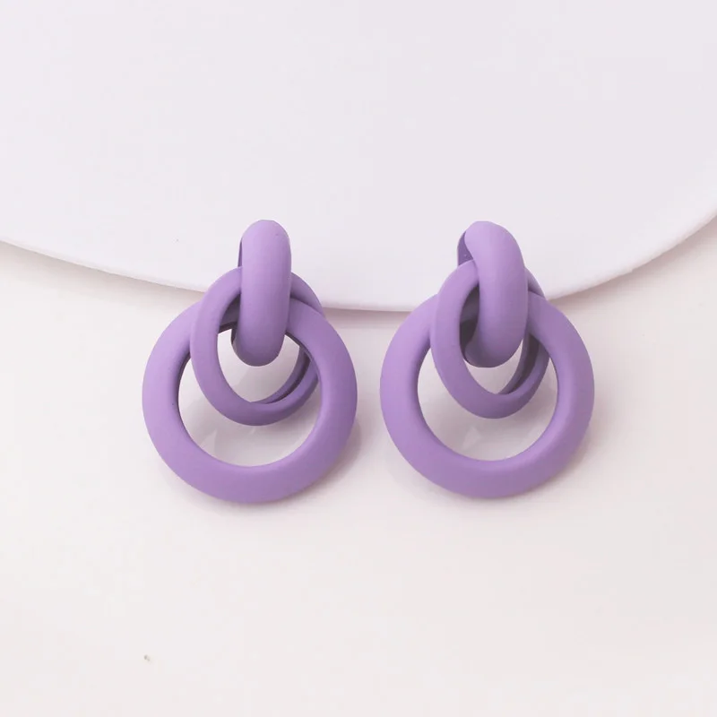 A pair of Purple Women's Dangle Earrings on a white surface.