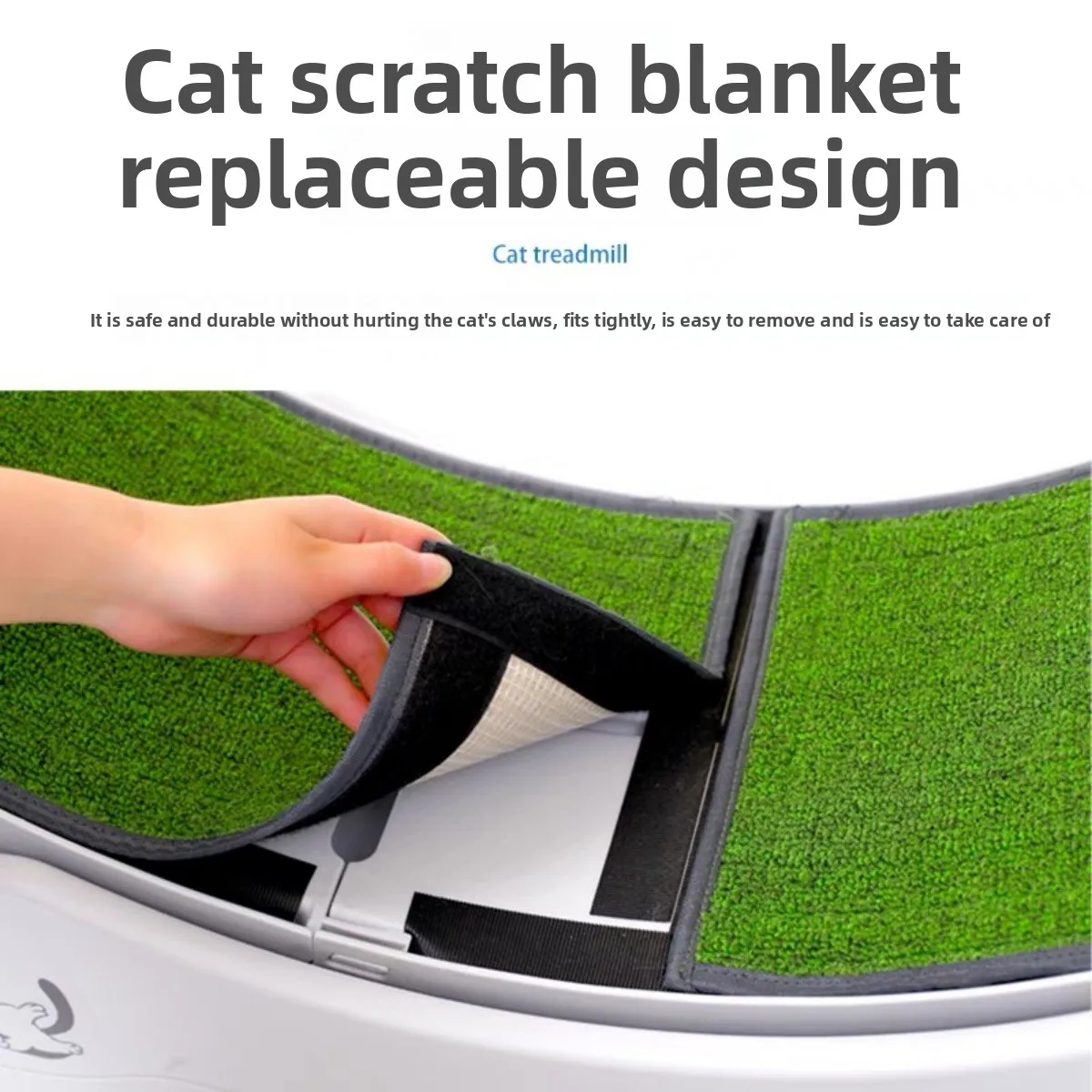 Close-up of the cat scratch blanket with a replaceable design. A hand is shown pulling up a section of the green artificial grass, which is attached to the white plastic wheel via a black hook-and-loop (Velcro) strip for easy cleaning.