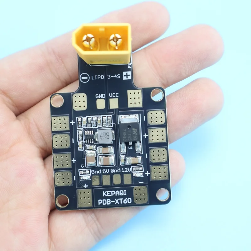 Détail du double BEC 5V/12V sur la carte PDB XT60, entouré de composants électroniques et de points de soudure.