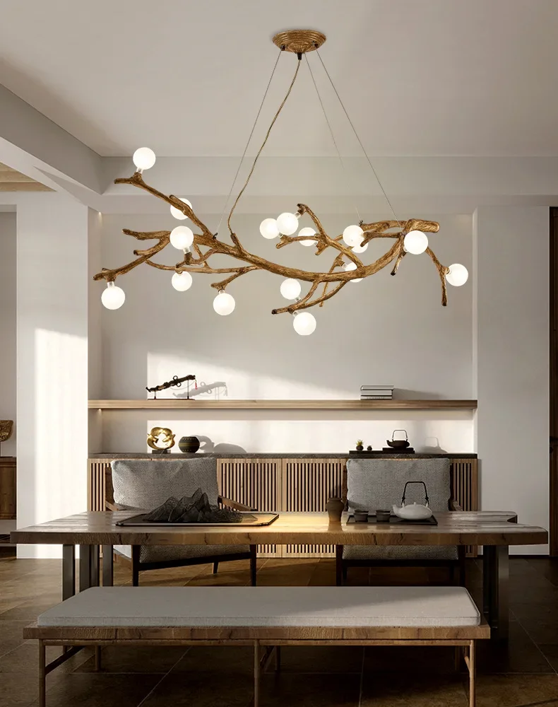 A modern dining room showcases a Branch Pendant Light with glass orb shades, a wooden table, cushioned benches, and a decorative shelf. This organic modern lighting elevates the ambiance, seamlessly merging natural elements with contemporary design.