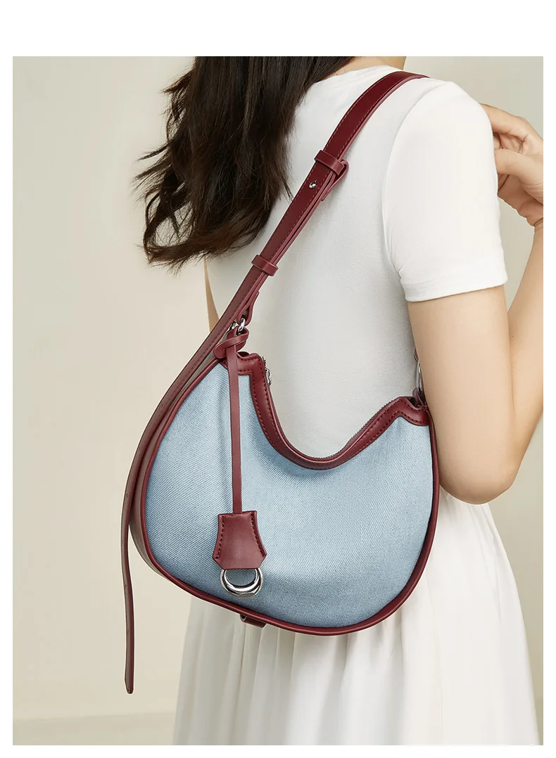 Woman carrying half moon shoulder bag made of denim with genuine leather trim – casual and stylish design for daily use.