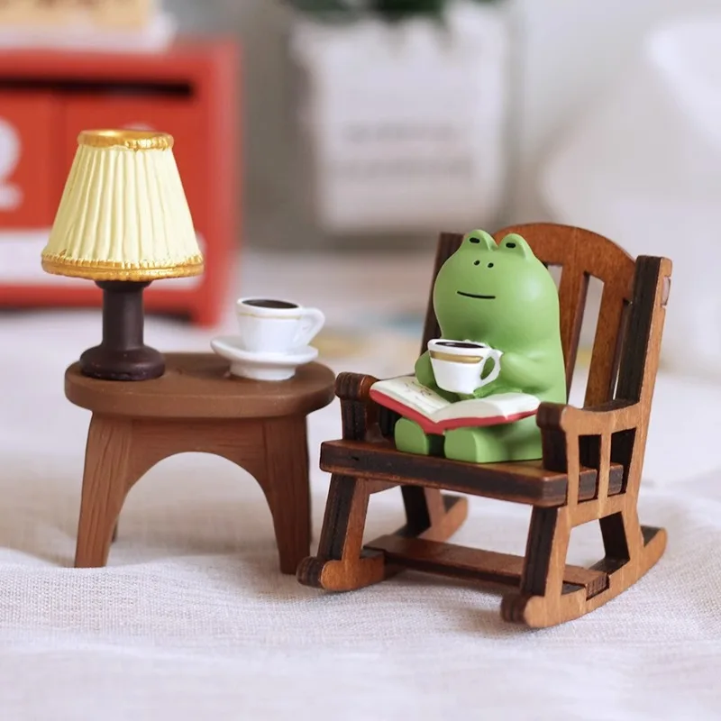 A small cute frog statue made of resin with a rocking chair design, holding a book and a cup of coffee, home decor for the bedroom...